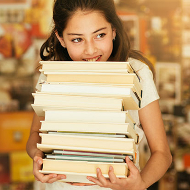 Girl holding stack of books in library