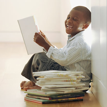 Boy sitting against wall reading a book